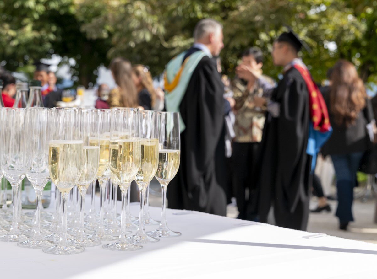 IMI Switzerland students celebrating graduation in academic regalia on campus in Lucerne, symbolizing international success and academic achievement.